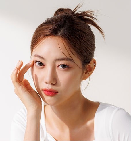 손끝으로 눈가를 짚은 여성 모델의 상반신