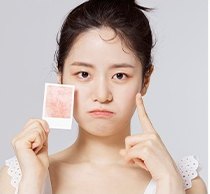 기름종이를 든 여성이 볼을 손가락으로 가리키며 찡그린 표정