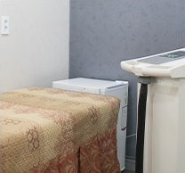 베이지색 커버를 덮은 시술 베드와 레이저 장비가 놓인 제모 전용룸 내부