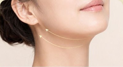 耳の下の顎のラインと首すじが一緒に見える女性の顔の3/4側面クローズアップ — 二重顎リフティングの施術部位